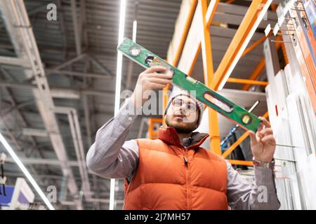 un uomo in un negozio di hardware sceglie un livello di bolla Foto Stock