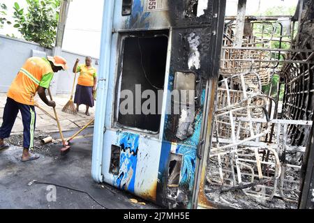 Colombo, Sri Lanka. 10th maggio 2022. I lavoratori puliscono la scena di un veicolo distrutto durante gli scontri a Colombo, Sri Lanka, 10 maggio 2022. Mahinda Rajapaksa si è dimesso lunedì come primo ministro dello Sri Lanka quando sono scoppiate violente proteste, e un coprifuoco a livello nazionale è stato imposto fino a mercoledì. Credit: Gayan Sameera/Xinhua/Alamy Live News Foto Stock