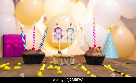 Bella carta di compleanno per una ragazza con un cupcake sullo sfondo di palloncini. Ragazza felice di compleanno, scatola del regalo sullo sfondo delle candele che bruciano. Foto Stock