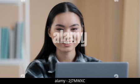 Ritratto asiatico sorridente soddisfatto ragazza utente studente freelancer acquirente blogger business donna 20s signora guardando laptop schermo sorriso sincero utilizzando Foto Stock