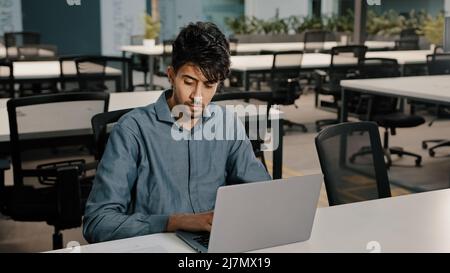 Giovane uomo scrittore arabo dipendente scrivere con cura tastiera portatile copiare testo in forma elettronica uomo concentrato controllo documenti originali scrittura Foto Stock