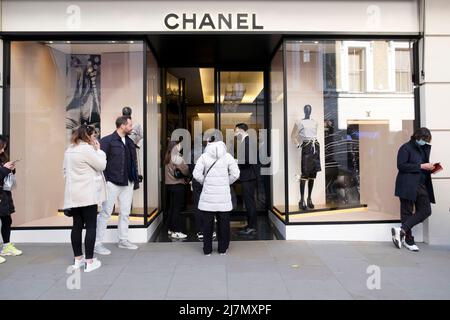 Persone clienti acquirenti coda fuori negozio Chanel a New Bond Street post pandemic a West London Inghilterra UK 2022 KATHY DEWITT Foto Stock