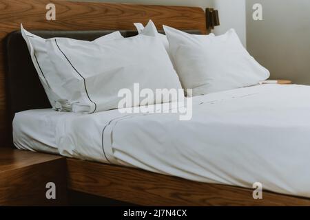 Cuscini e lenzuola bianchi in una camera da letto in un salone di bellezza. Chiudi. Ampio letto matrimoniale per un sonno confortevole e un relax. Moderno e confortevole cotone bianco Foto Stock