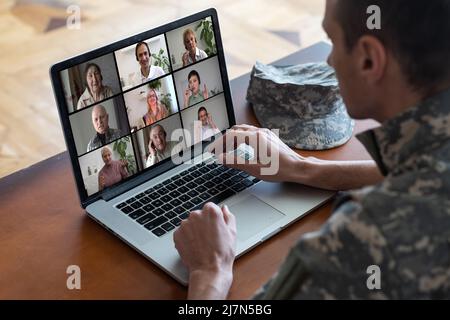 Un uomo soldato felice sorridendo mentre si fa una chiamata in conferenza su un computer portatile al chiuso Foto Stock