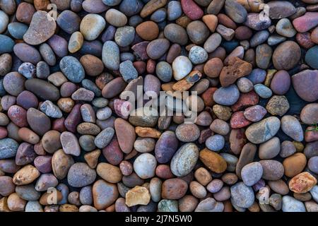 Sfondo minerale con pietre di fiume in colori muti sparsi uniformemente sul terreno, alto angolo di vista ravvicinata di piccoli ciottoli disposti piatto Foto Stock