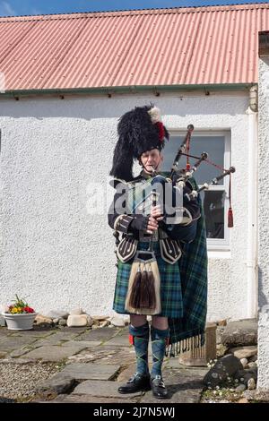 Suonatore maschile di cornamusa indossando un tradizionale costume scozzese: Tartan kilt blu e verde e accessori, Kilberry, Scozia, Regno Unito Foto Stock