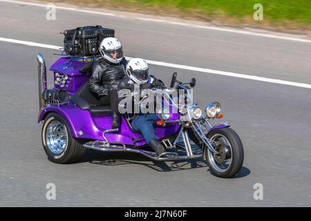 Una moto chopper viola Custom Delta VW Beetle Trike con una ruota davanti, e due dietro, guidando sulla M61 a Manchester, Regno Unito Foto Stock