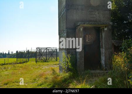 Parte inferiore di un'antica torre di guardia di confine con una porta d'ingresso arrugginita su un'ex fortificazione di confine della GDR, all'angolo di tre paesi di Assia, Thuring Foto Stock