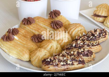 Eclairs fatti in casa con crema. Si trovano su un piatto. Pasticceria con crema. Primo piano. Foto Stock