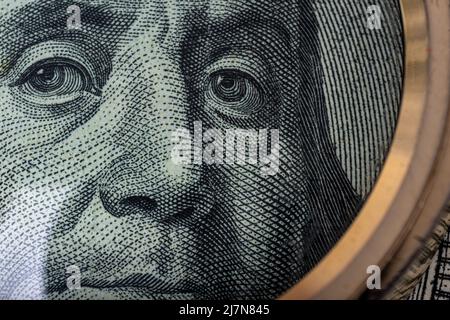 Primo piano ritratto di ben Franklin sulla fattura da 100 dollari USA sotto una lente d'ingrandimento. Benjamin Franklin su una banconota americana da cento dollari, vicino Foto Stock