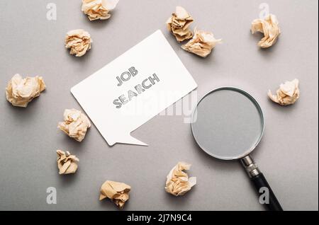 Ricerca di lavoro di parole e lente di ingrandimento su sfondo grigio Foto Stock
