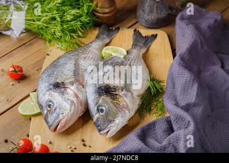 Pesce dorado sbucciato crudo con ingredienti da cucina. Pesce fresco su sfondo di legno. Foto Stock