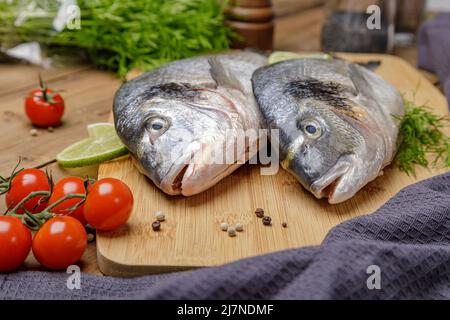 Pesce dorado sbucciato crudo con ingredienti da cucina. Pesce fresco su sfondo di legno. Foto Stock