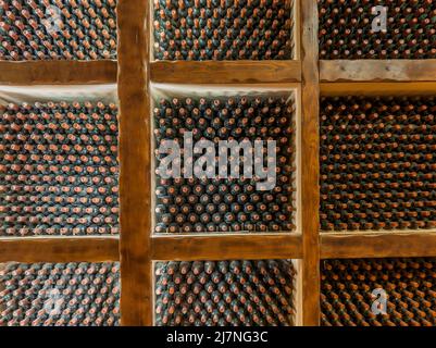 Vecchie bottiglie di vino che maturano in una cantina volta Foto Stock