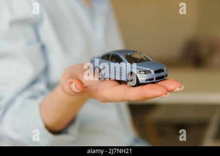Assicurazione auto. Donna che tiene in mano un'auto giocattolo. Foto Stock