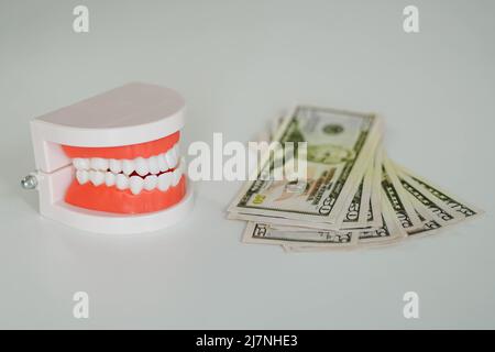 Mandibola artificiale dentale con mucchio di banconote in dollari. Concetto di cura dentale costoso. Foto Stock