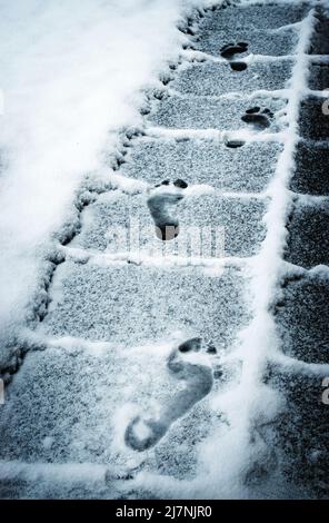 sfondo stagionale impronte piedi sul marciapiede innevato Foto Stock
