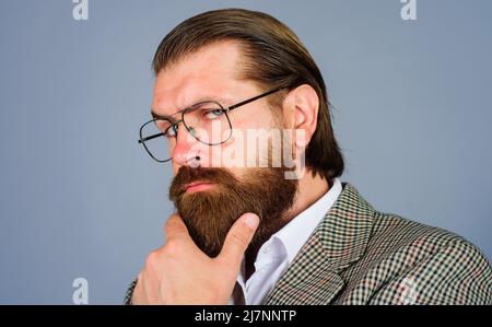 Uomo con bearded premuroso in occhiali. Uomo d'affari in occhiali con mano sul mento. Moda uomo. Foto Stock