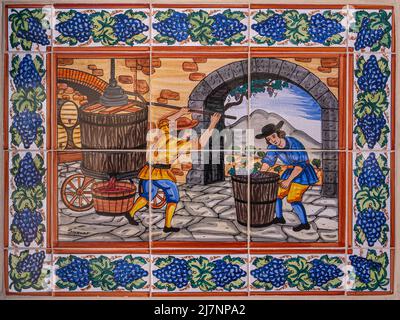 Temecula, CA, USA - 12 aprile 2022: Europa Village. Pittura murale di mattonelle, fase 5/6 di vinificazione. Colori caldi che mostrano 2 figure. Bordo blu dell'uva Foto Stock