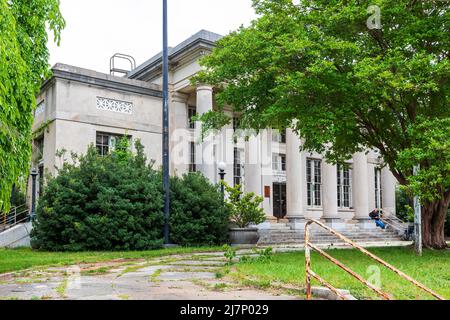 LEXINGTON, NC, USA-8 MAGGIO 2022: Edificio della Biblioteca della contea di Vintage Davidson. Un uomo si siede sui gradini con sedia a rotelle nelle vicinanze. Foto Stock