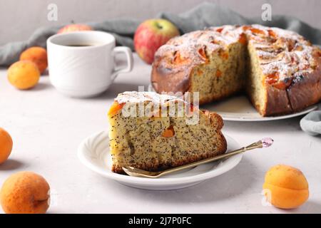 Torta fatta in casa con semi di papavero, albicocche e mele con una tazza di caffè su sfondo grigio Foto Stock