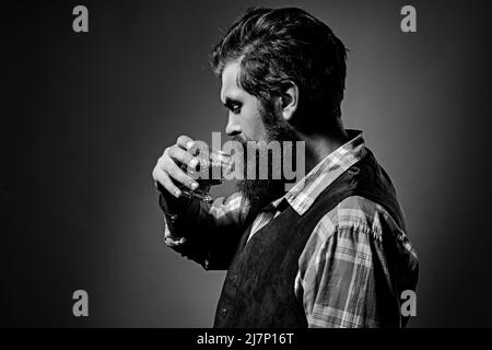 Uomo barman con barba tiene il brandy di vetro. Bevanda alcolica di lusso. Foto Stock