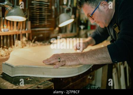 luthier lavora su un tavolo frontale a doppio basso fatto a mano nella sua officina Foto Stock