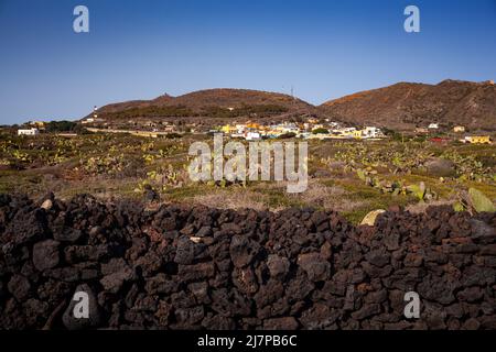 Vista caratteristica del muro di pietra arenaria costruito con pietre laviche, sullo sfondo la città di Linosa Foto Stock