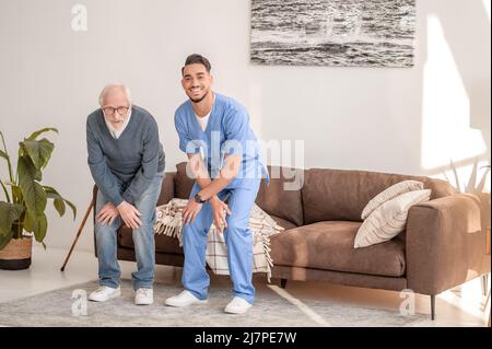 Uomo anziano che si esercita con un terapista fisico esperto Foto Stock