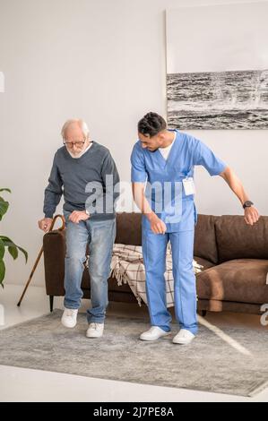 Paziente anziano concentrato che esercita con il suo fisioterapista Foto Stock