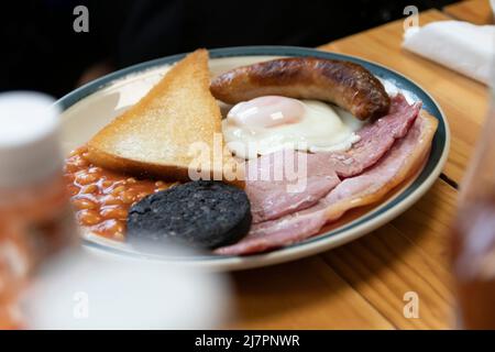 Colazione all'inglese completa, conosciuta anche come "friggitrice", composta da uova, salsiccia, pancetta, fagioli, toast, e pudding nero. Foto Stock