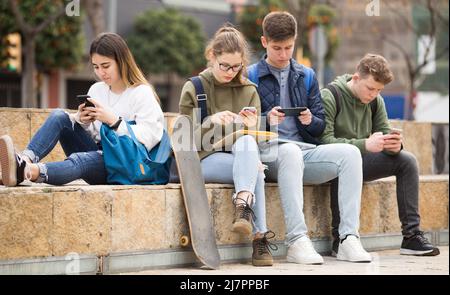 Gruppo di ragazzi che utilizzano gli smartphone all'aperto Foto Stock