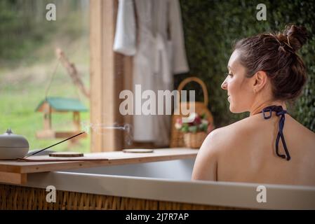 Donna in vasca idromassaggio godendo il profumo di incenso Foto Stock