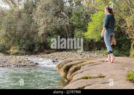 Donna che cammina sulle rocce a base di scarpe in mano Foto Stock