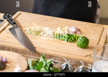 Le spezies thailandesi, l'erba di limone, l'aglio, lo scalogno, il bergamotto e la paprika, sono state preparate per cucinare tagliando sul tagliere. Foto Stock