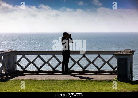 Un uomo con un paio di binocoli che guardano il mare Foto Stock