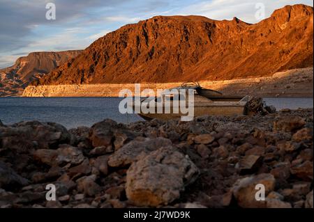 10 maggio 2022 - Lake Mead National Recreation Area, Nevada, Stati Uniti - Una barca precedentemente sommersa è visto poggiare su terra asciutta vicino a un ''anello della vasca'' di depositi minerali lasciati dai livelli più alti dell'acqua lungo il lago Mead colpito dalla siccità all'area di ricreazione nazionale del lago Mead, 10 maggio 2022, Vicino a Las Vegas, Nev. il Bureau degli Stati Uniti di Reclamation ha riferito che il lago Mead, il più grande serbatoio artificiale del Nord America, è sceso a circa 1.052 piedi sopra il livello del mare, il più basso è stato da allora essere riempito nel 1937 dopo la costruzione della diga di Hoover. Due serie di resti umani sono stati scoperti recentemente come Foto Stock