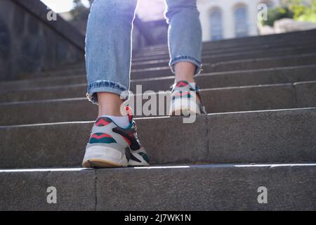 Sneakers di giovane donna sale scale nella città moderna Foto Stock