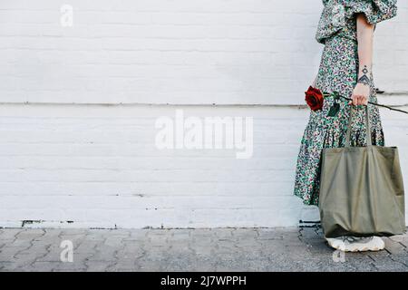 Stile di vita sostenibile, senza sprechi, senza plastica. Mockup, banner web con ritratto senza volto di donna che tiene borsa di alimentari in cotone e rosa rossa su bianco Foto Stock