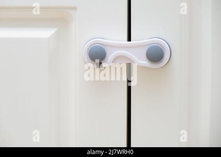 Porte di armadi da cucina bianchi bloccati dai bambini. Bloccare i cassetti  dei mobili del bambino Foto stock - Alamy