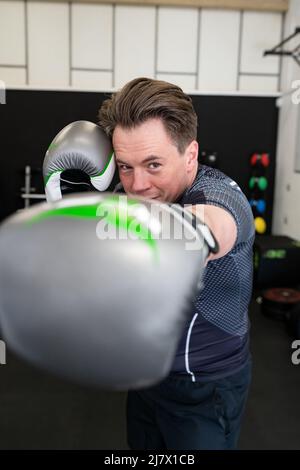 Ipswich Suffolk UK Aprile 03 2022: Giovane uomo in forma che lancia un jab verso la fotocamera indossando guanti da boxe Foto Stock