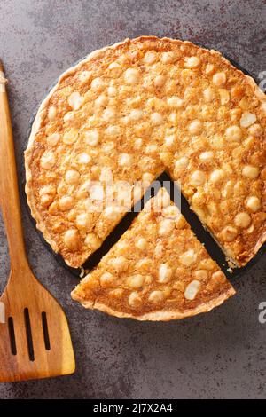 Noci di crostata di macadamia e cremoso ripieno d'oro di lusso e cotto in un macerato casereccio pasta frolla primo piano nel bordo sul tavolo. Verticale Foto Stock