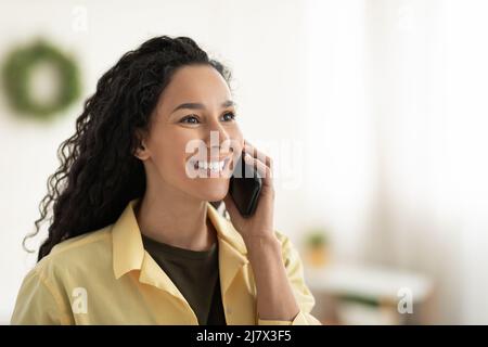 Donna sorridente che parla al telefono cellulare a casa Foto Stock