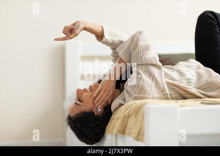 Donna eccitata che ascolta musica in cuffia e balla Foto Stock