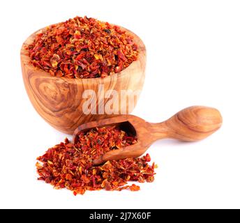 Fiocchi di paprika rossa essiccati in ciotola di olive e scoop, isolati su sfondo bianco. Spezie ed erbe Foto Stock