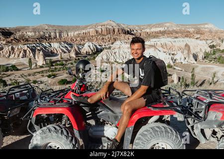 Giovane maschio caucasico in Cappadocia Turchia in un tour di gruppo con un ATV rosso Foto Stock