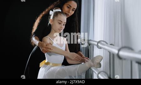 Coreografo femminile insegnante mentore trainer di danza classica insegna aiuto postura con stretching a giovane studente imparare ballare teen girl ballerina Foto Stock