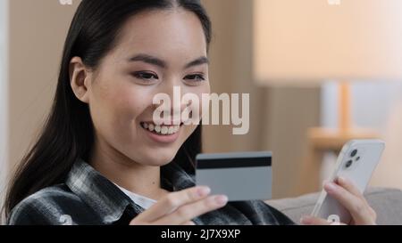 Asian Korean Japanese Chinese ragazza millennial donna con carta di credito bancario e telefono cellulare che fanno transazione online pagamento elettronico shopping Foto Stock