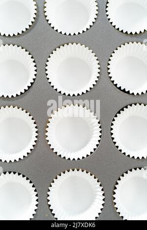 Foderare la teglia per cupcake con i fodere per preparare i cupcake di s'mers. Foto Stock
