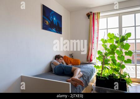 ragazzo che si rilassa sul letto con lo smartphone Foto Stock